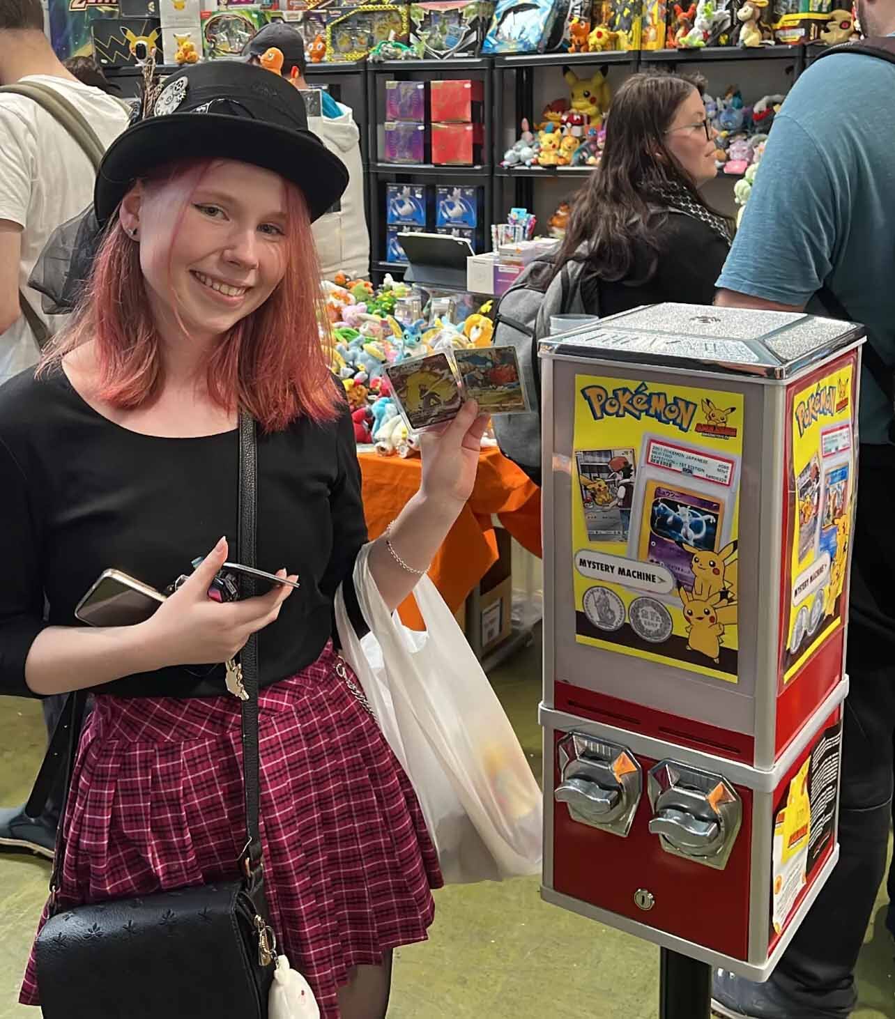 Besucherin mit gezogener Pokémon-Karte neben der AMAZINGTOYS® Pokémon Mystery Machine
